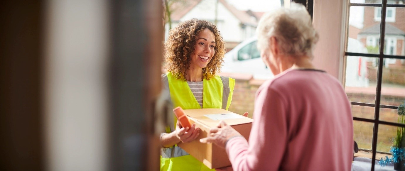 Delivery person handing a package to an elderly woman